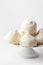 Home baked meringue cookies on cake stand on white table wall background. French Italian Swiss desserts cuisine confection