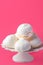 Home baked meringue cookies on white cake stand on pink background