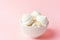 Home baked meringue cookies in white ceramic vintage bowl on gradient light pink background. French Italian Swiss cuisine desserts