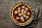 Home baked puff pastry Christmas tart with plum cinnamon jam filling decorated with stars. Dark wooden table linen kitchen towel