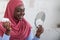 Home beauty treatment. Black muslim lady in hijab holding moisturising cream jar