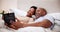 Home, bed and black couple with a tablet, love and morning with connection, smile and laughing. Bedroom, man and woman