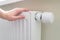 Home central heating system. Woman holds hand on the radiator