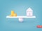 Home and coin stacks on balancing scale on blue background. Real estate business mortgage investment and financial loan concept.