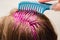 Home coloring of blonde hair: pink paint is applied to the head, hands in gloves hold a comb