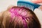 Home coloring of blonde hair: pink paint is applied to the head, hands in gloves hold a hairbrush