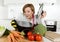 Home cook woman in red apron at domestic kitchen holding cooking pot with hot soup smelling vegetable stew