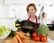 Home cook woman in red apron at domestic kitchen holding cooking pot with hot soup smelling vegetable stew