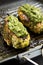 Home cooked chimichurri chicken breast in a grilling pan on a black background, side view. Close-up