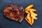 Home Cooked Medium rare grilled Beef steak Ribeye with roasted potato. on blue stone background