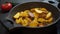 Home cooking background. Fatty food. Appetizing rustic yellow unpeeled potatoes cooked with olive oil fried in a pan