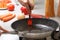 Home cooking. A woman oiling an oil pan on a gas stove, next to fresh vegetables and pasta