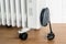 Home electric oil heater on plastic twin wheels and with cable reeled up on a cable storage. White oil-filled radiator on a brown