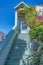 Home entrance with stairs near shrubs leading to a porched with picture windows at San Francisco, CA