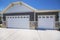 Home exterior with white double garage doors with windows and half stone walls