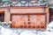 Home facade with snowy balcony above panelled metal garage door beside stairs