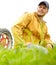 He is at home on the farm. A farmer kneeling in a field with his tractor parked behind him.