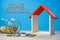Home Financial Conceptual. Model of house and coins on the wooden table with blue background.