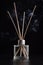 Home fragrance diffuser with reed sticks on black background with smoke