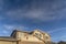 Home with front gable roof and dormers against vast blue sky with clouds