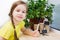 Home gardening concept. Girl holding a set of garden tools for planting plants on the background of paper pots and plants