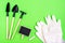 Home gardening. Miniature gardening tools: scoop, rake, inscription board and chalk, garden gloves on green cardboard.