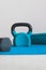 Home gym concept, blue yoga mat with kettlebell foam roller and dumbbell shot at shallow depth of field from low perspective