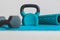 Home gym concept, blue yoga mat with kettlebell foam roller and dumbbell shot at shallow depth of field from low perspective