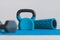 Home gym concept, blue yoga mat with kettlebell foam roller and dumbbell shot at shallow depth of field from low perspective