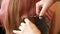 Home hairdressing salon. Close-up of father`s hands cutting the long hair of an adult Caucasian daughter.