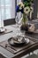 Home Inerior with dining room table setting with black stainless cutlery and ceramic tableware setting on nartual walnut wood top