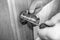 Home installation and repair of round metal door handle. Men& x27;s hands tighten the screws on the door handle with a