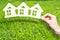 Home insurance concept with hand holding house shaped printouts on green grass