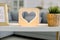 Home interior in living room. Close up image of decorative stylish wooden night lamp with heart picture, on table with