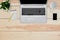 Home interior. Top view of wooden desk with laptop, cell phone, blank notebook for text and pencil, empty white mug and green flow