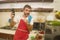 Home lifestyle portrait of young happy and attractive home cook man in red apron following online recipe on internet mobile phone