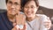 Home loan and financial concept - Close up wooden home toy in hand with blurred asian couple smiling for home loan success