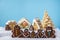 Home made delicious traditional gingerbread village and gingerbread man family blue background.