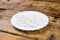 Home made fresh large cottage cheese on white plate on wooden background. Side view.