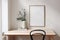 Home office concept. Old books, empty vertical wooden picture frame mockup hanging on white wall. Wooden desk, table