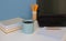 Home office of a creative entrepreneur with black laptop. Modern creative workspace with blue cup of coffee or tea, wooden pen and