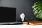 Home office desk table workspace with a notebook, light bulb, pen, cup coffee, green leaf monstera and eyeglasses