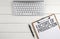 Home office workspace with keyboard, clipboard and pen with text FACTORS OF PRODUCTION on white wooden background , business