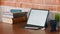 Home office workspace tablet, books, coffee, notebook and plant on wooden table.