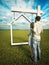 Home ownership dream. A couple standing before a real estate home sign with a grass field and beautiful sky background.