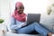 Home Pastime. Black Muslim Woman In Hijab Relaxing With Laptop And Coffee