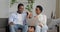 Home portrait of young African American family parents with small daughter sitting in living room interior in cozy house