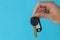 Home purchase concept. Keys with a keychain with place for text in hand on a blue background