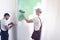 Home renovation worker with a tool belt painting a wall green wi