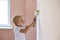 Home renovation. Young boy painting interior wall with paint roller